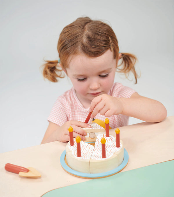 This wooden cake toy set includes a 6-piece, sliceable cake with velcro, 6 pretend candles, a tray and a toy cake slicer.